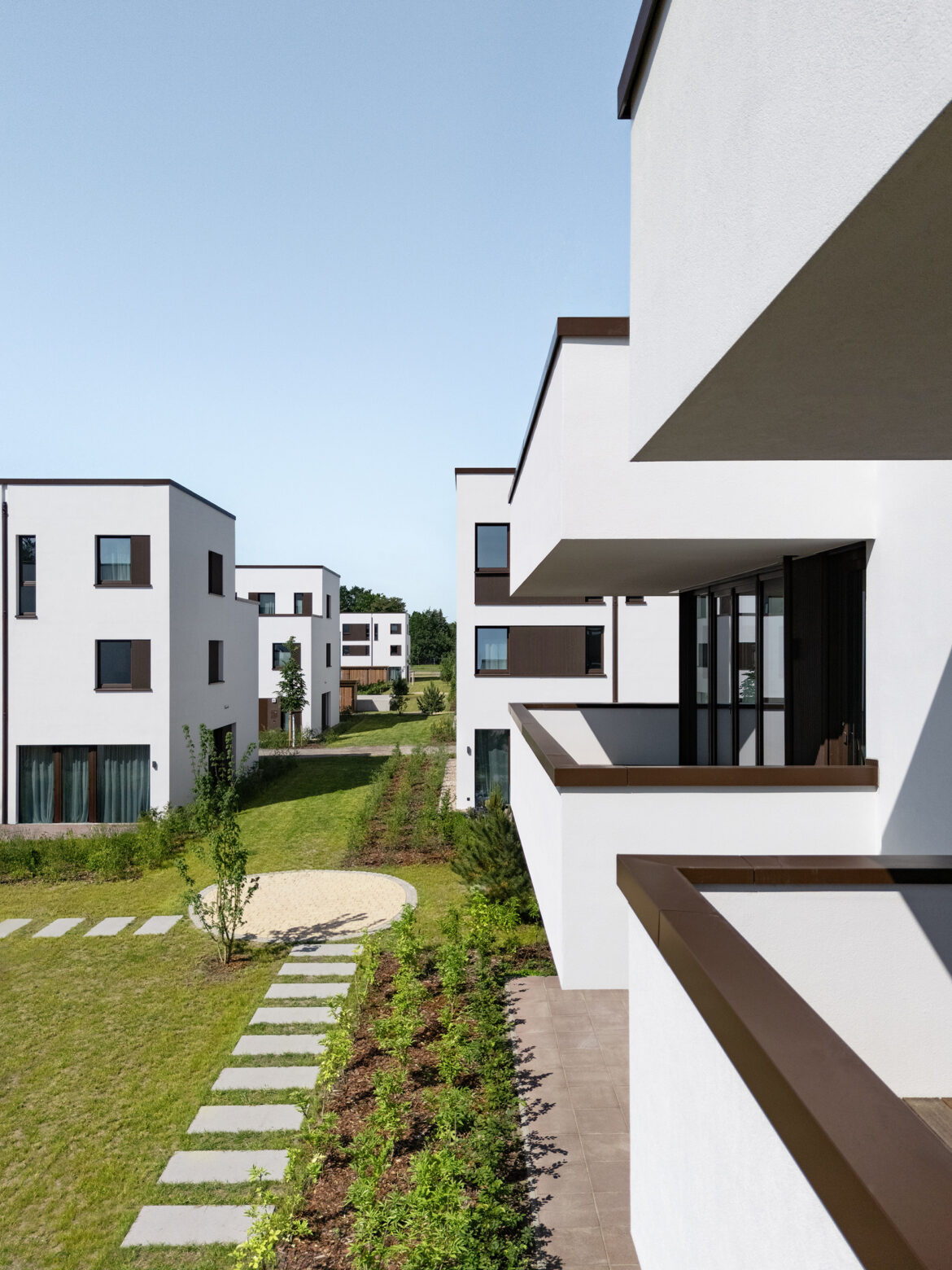 Wide view of a modern residential development with white façades, terraces, and landscaped communal areas