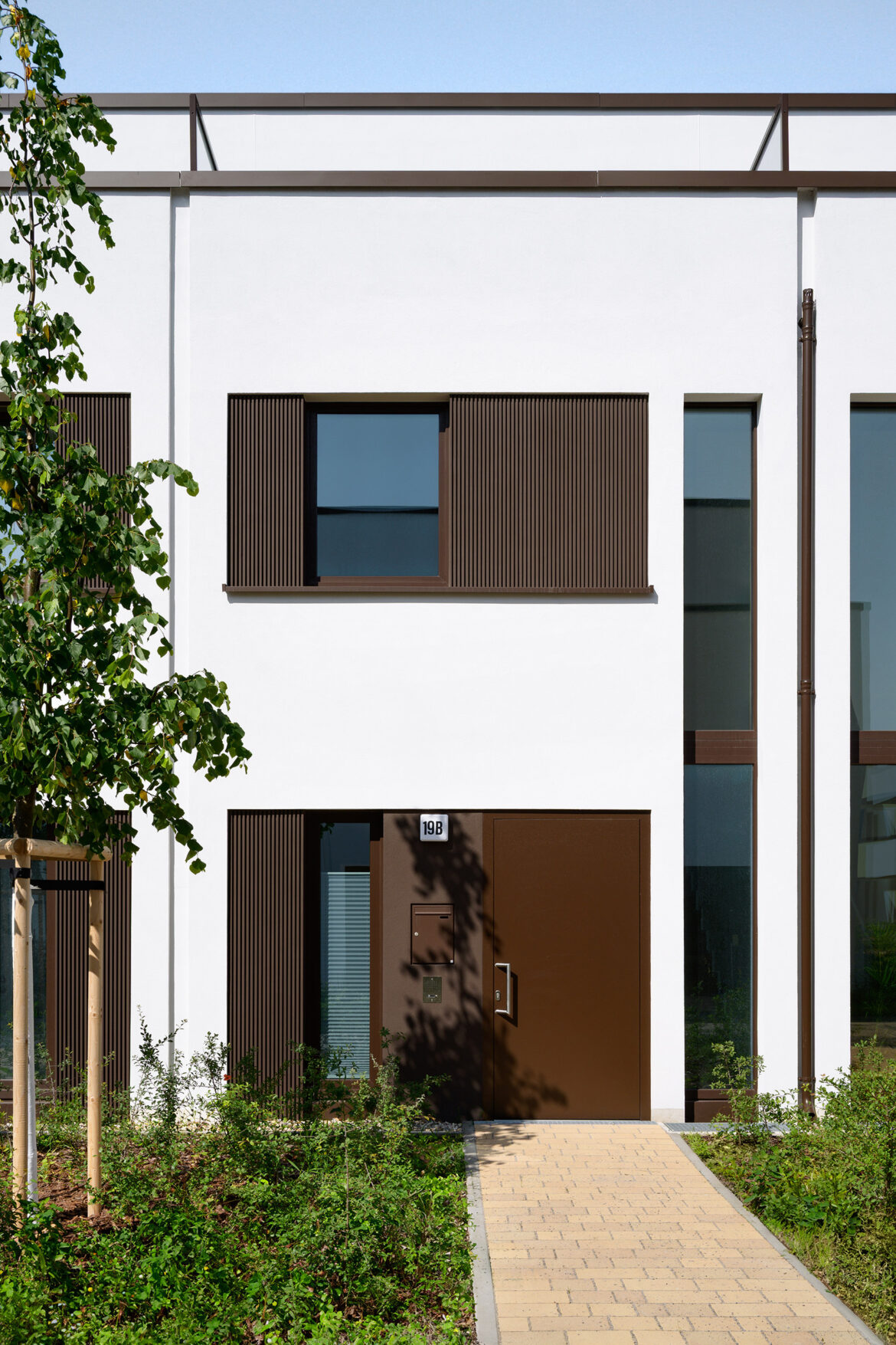 Wide view of a modern residential development with white façades, terraces, and landscaped communal areas