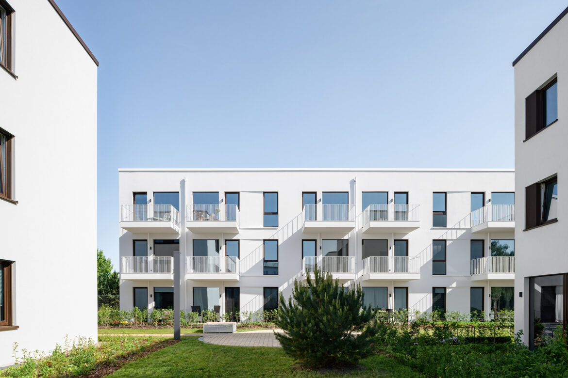 White residential facade with dark window frames and clean geometric balconies