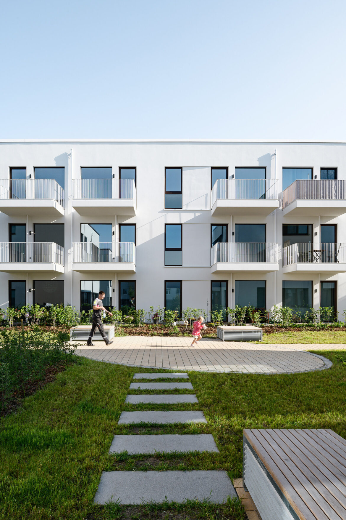 Contemporary residential building photographed from garden level with lawn, trees, and landscaped surroundings